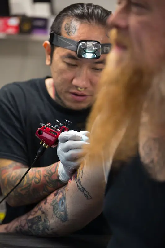 Thu Vo Le focusing on tattooing a client with precision